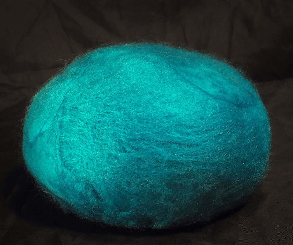 A large, bright blue, blob-like doll with a needle felted surface. The shape is plain, round, and easily squished.